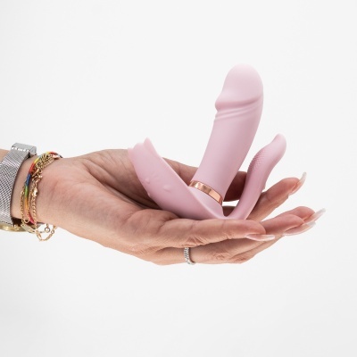 Vibrador rosa em silicone segurado por uma mão em fundo branco