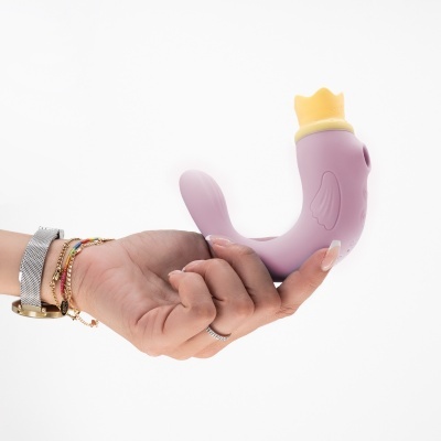 Vibrador cor-de-rosa em forma de pato com coroa amarela na mão