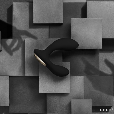 Produto curvo negro com detalhes dourados sobre azulejos cinzentos