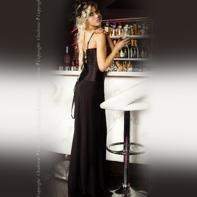 Mulher em vestido preto longo ao lado de balcão branco com banquetas altas em bar