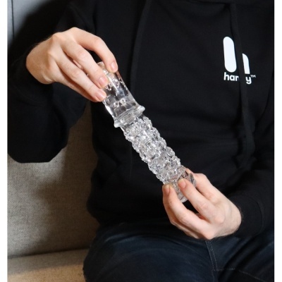 Pessoa segurando objeto cilíndrico de plástico transparente com textura em relevo