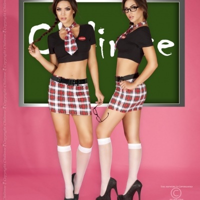 Duas mulheres vestem conjunto escolar xadrez, top preto, meias brancas e sapatos pretos com fundo rosa e quadro verde