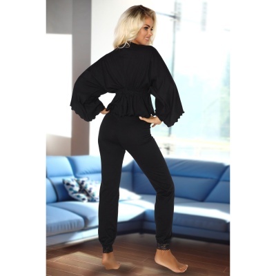 Conjunto feminino preto com top de mangas largas e calças justas em sala com sofá azul