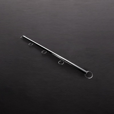 haste metálica prateada com quatro argolas circulares sobre superfície escura