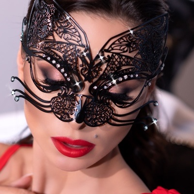 Máscara preta filigranada de gato com brilhos numa mulher com batom vermelho