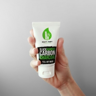 Tubo branco de máscara facial peel-off com texto em verde e preto, segurado por mão