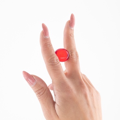 Mão feminina a usar anel vermelho brilhante