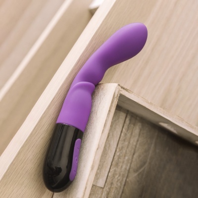 Vibrador roxo e preto numa gaveta de madeira clara