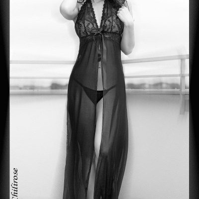 Vestido de noite preto transparente com corpete rendado e laço, usado por modelo de pé num espaço exterior