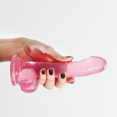 Dildo rosa translúcido com base de ventosa segurado por uma mão