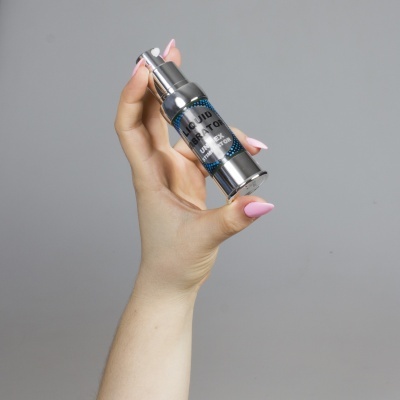 Frasco metálico prateado com conta-gotas LIQUID CREATINE SALE-U na mão de mulher