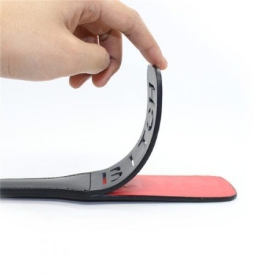 Palmilha fina preta e vermelha com texto BATA, segurada e dobrada por uma mão sobre fundo branco