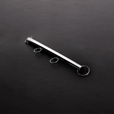 Barra metálica prateada com três argolas fixas sobre fundo preto texturizado