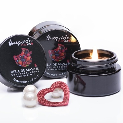 Vela de massagem preta com rótulo de frutas vermelhas, duas pérolas e um coração vermelho pequeno