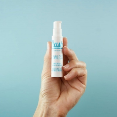 Frasco branco de produto para pestanas com texto azul segurado pela mão contra fundo azul claro