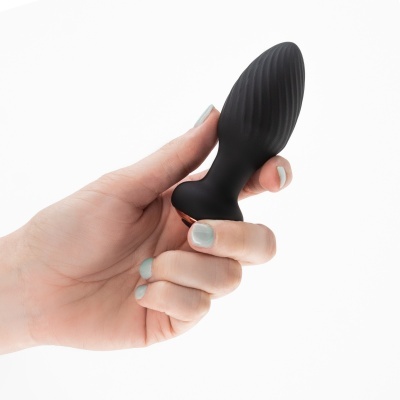 Plug anal preto de silicone com textura estriada segurado por mão com unhas azuis