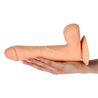 Dildo realista cor de pele com base de ventosa e textura, segurado por mão com unhas cor de rosa