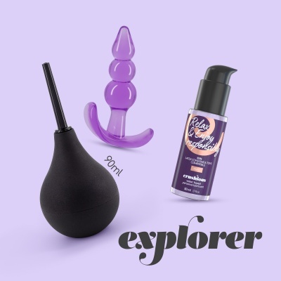 Produtos eróticos: pera de lavagem preta, plug anal roxo em silicone, frasco dispensador roxo com texto, fundo lilás