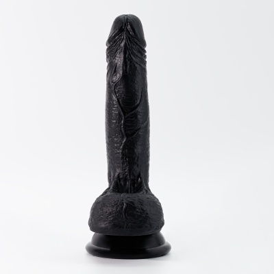 Dildo preto texturizado com base preta em fundo branco.