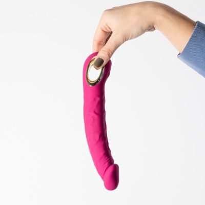 Vibrador rosa em silicone com detalhe dourado, segurado por uma mão