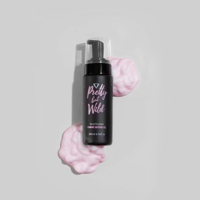 Frasco preto de espuma para o corpo Pretty but Wild com espuma rosa sobre fundo cinza.