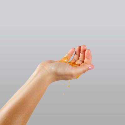 Mão segurando líquido amarelo espesso a cair