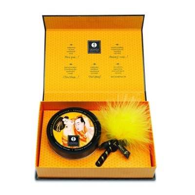 Conjunto de presente com frasco redondo decorado e acessório com penugem amarela num estojo laranja.