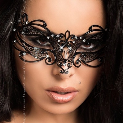 Mulher a usar máscara preta decorativa com cristais sobre fundo neutro