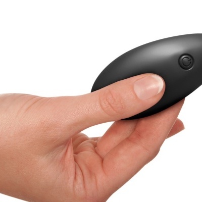 Dispositivo preto oval com botão, segurado por mão contra fundo branco