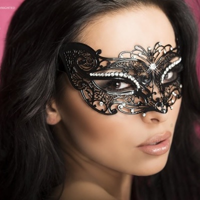Máscara preta decorativa em renda com brilhos prateados usada por mulher com cabelo escuro
