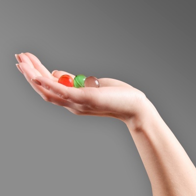 Mão humana segurando três esferas coloridas