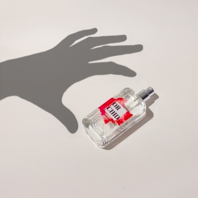 Frasco de perfume transparente com rótulo FOR HIM e sombra de mão