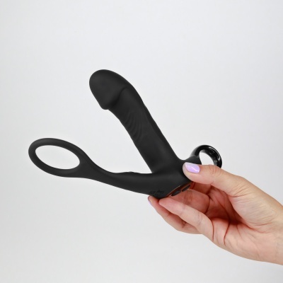 Produto sexual em silicone preto com formato anatómico segurado por mão com unhas lilás