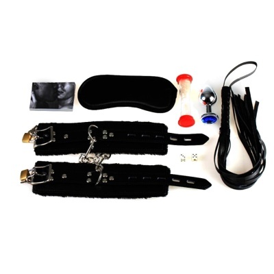 Conjunto de acessórios bondage preto com venda, algemas, ampulheta, plug anal, chicote e dados associados.