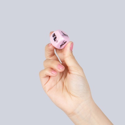 Mão feminina segurando dado rosa com imagens de yoga