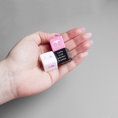Três dados coloridos preto, branco e rosa com texto em inglês e uma imagem de lábios na mão de uma pessoa