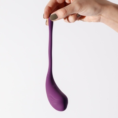 Vibrador de silicone roxo curvado segurado por mão com fundo branco
