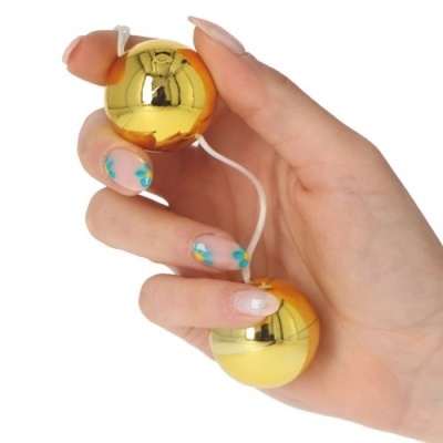 Bolas douradas brilhantes ligadas por fio branco seguradas por mãos femininas com unhas decoradas.