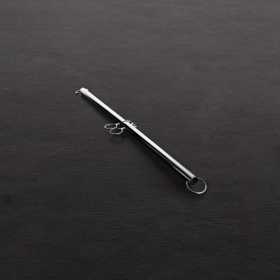 Bastão metálico prateado com anel sobre superfície preta texturizada