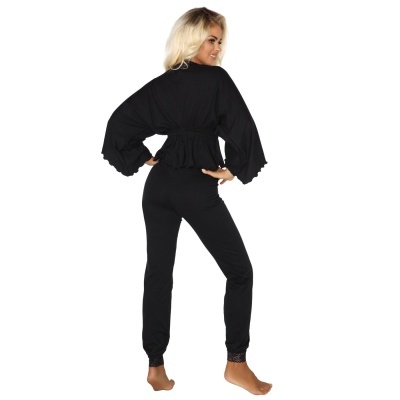 Mulher vestindo conjunto preto com calças justas e parte superior de mangas largas