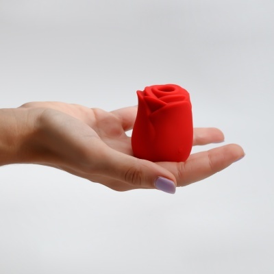 Vela vermelha em formato de rosa na mão de uma mulher com unha lilás