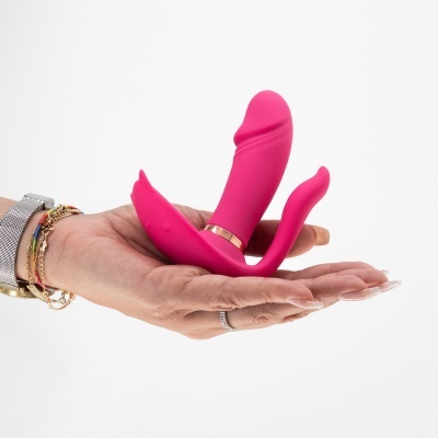 Vibrador cor-de-rosa de silicone com detalhes dourados, na mão, fundo branco