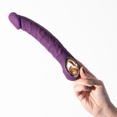 Vibrador roxo em silicone com base dourada segurado por mão