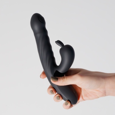 Vibrador preto texturizado com estimulador em forma de coelho na mão
