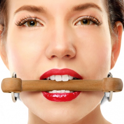 Mulher com batom vermelho segura objeto de madeira na boca em fundo branco