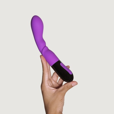 Vibrador roxo com base preta segurado por uma mão.