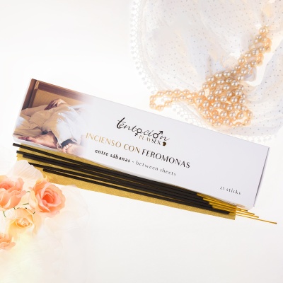 Caixa de incenso com feromonas e paus de incenso em fundo claro com flores e lenço branco.
