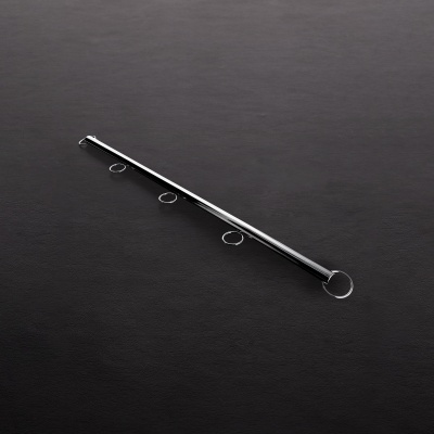 haste metálica prateada com quatro argolas circulares sobre superfície escura