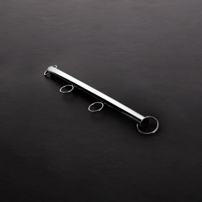 Barra metálica prateada com três argolas fixas sobre fundo preto texturizado