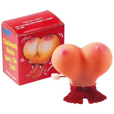 Brinquedo em forma de seios com base pés vermelhos e caixa vermelha com texto